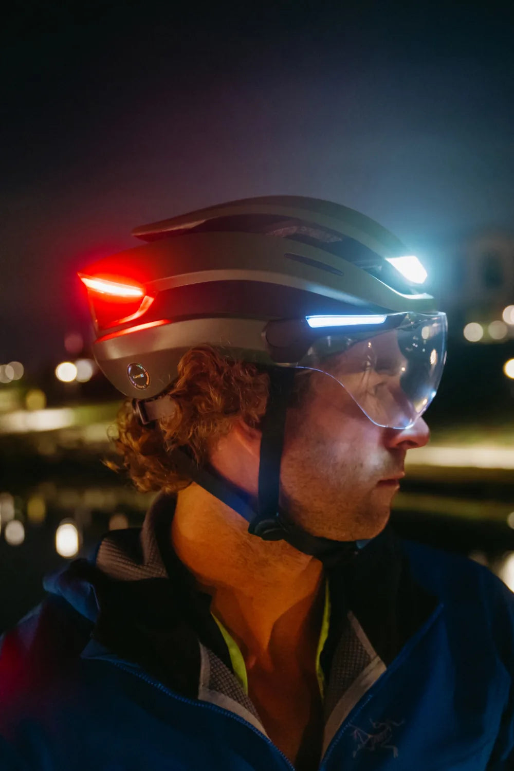 Rider at night wearing Lumos Ultra E-Bike in Emerald Green with the lights on